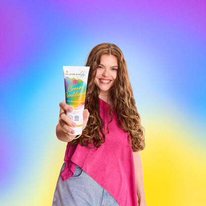 Smiling woman with long wavy hair holding hair cream conditioner against colorful background