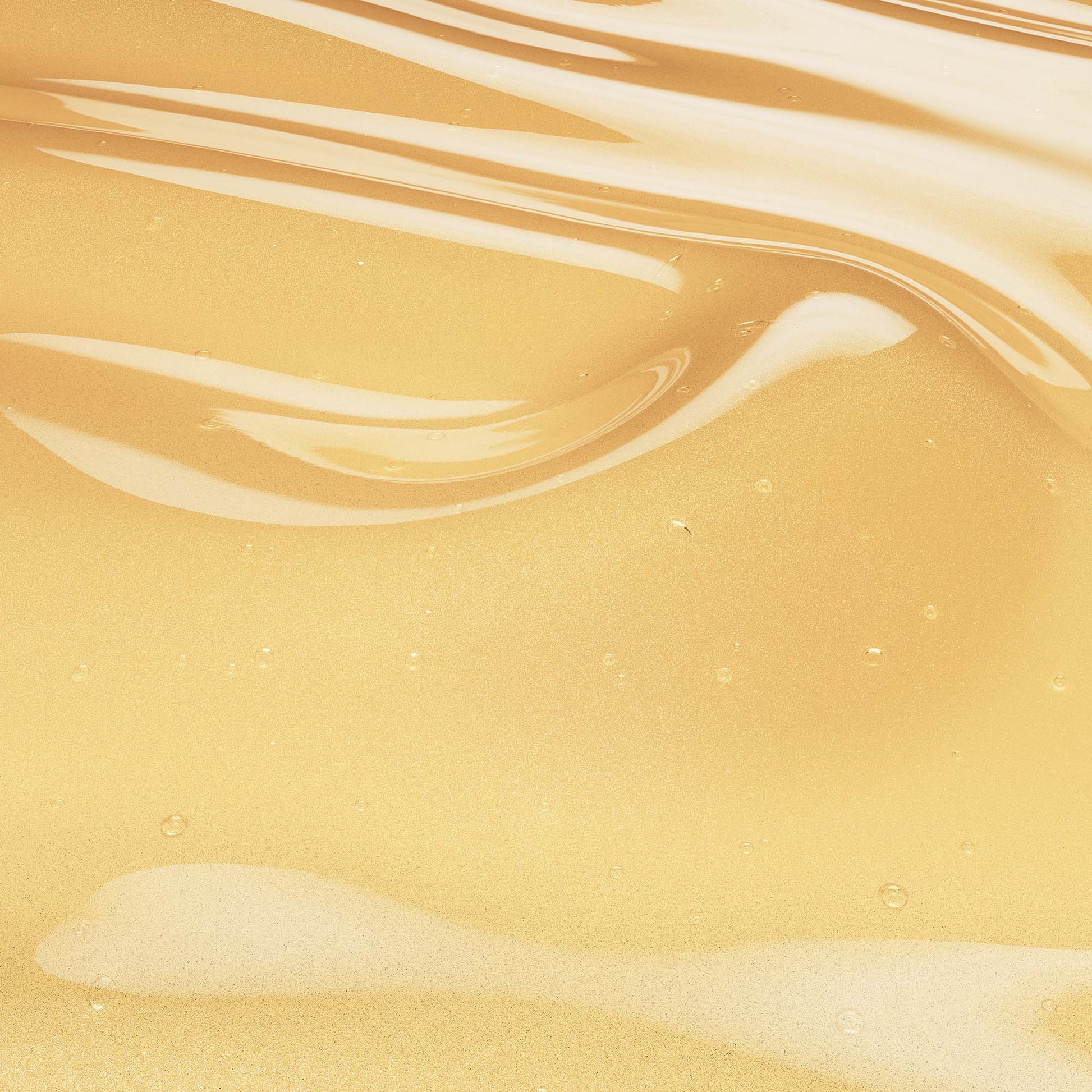 Golden honey hair serum texture with smooth, wavy surface and glossy finish